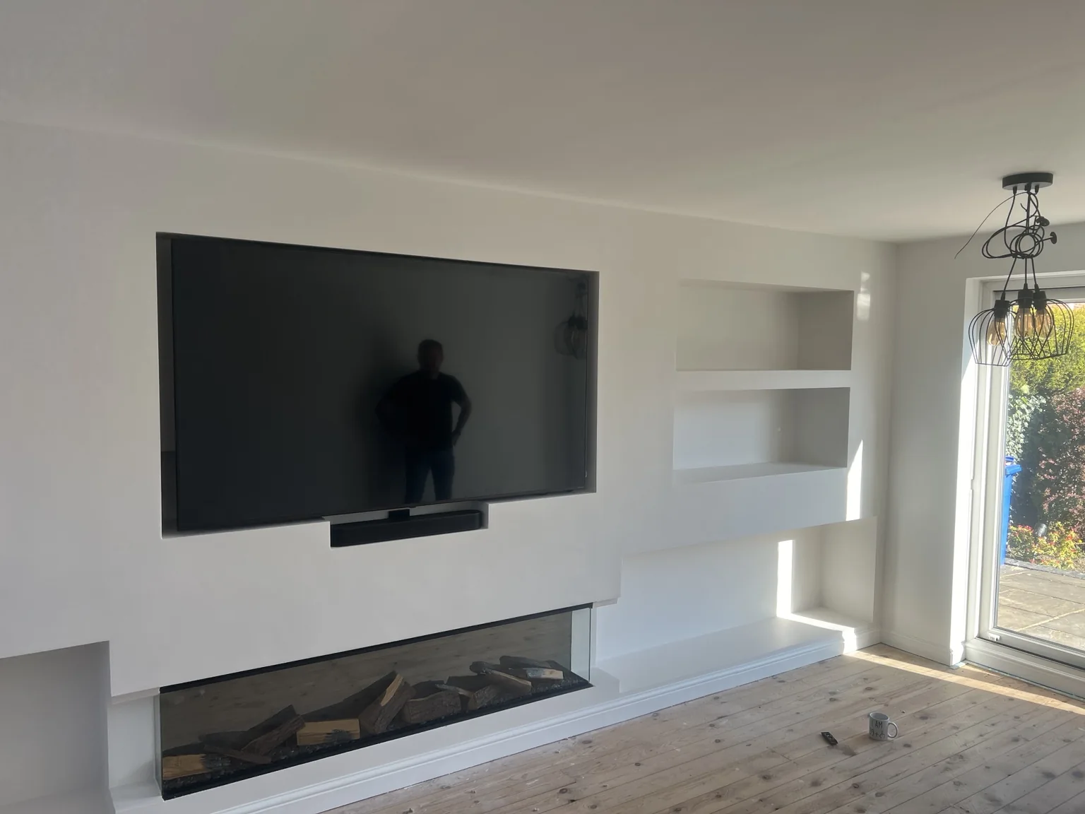 Custom white media wall with TV, shelving and fire